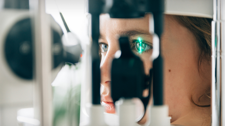 Face of young white patient getting eyes assessed using ophthalmologist equipment